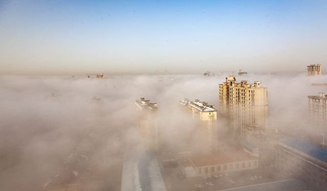 图为2015年12月2日，摄影师在河南滑县供电公司65米高的大楼上拍下城市雾海景观。