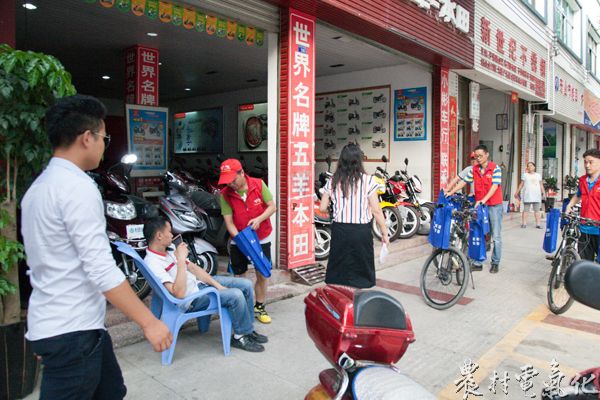 2、6月16日，余庆县乌江中路的电瓶车商铺，志愿者正在为商家宣传用电节能、赠送节能灯，代步的自行车就停在近旁。（王仁磊 摄）.jpg