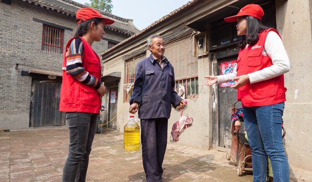 图为10月17日，河南滑县电力小红帽青年志愿者在该县瓦岗乡刘庄，为孤寡老人送去肉和油。