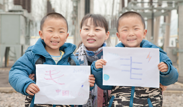 2月14日，“家属看电网”活动最后，职工家属张敏带着双胞胎儿子刘洪瑀、刘洪瑞展示刚刚完成蜡笔画。