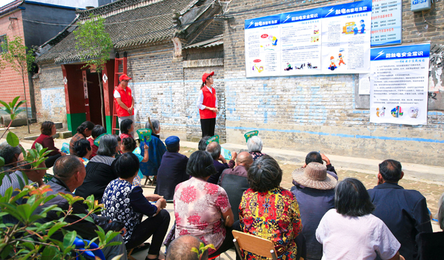 图4为2017年5月24日，河南周口，当地供电公司“小红帽”青年志愿者正在为留守老人讲解电力安全知识。